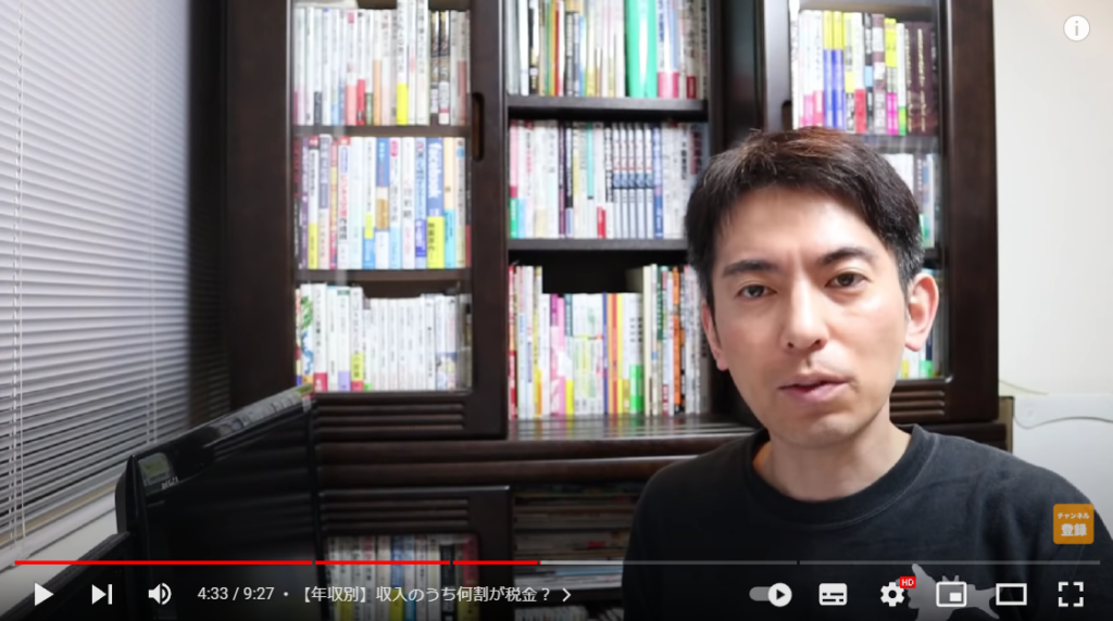 年収別の税負担額を発表しようとしている場面。山田さんが本棚の前に座って話している様子。