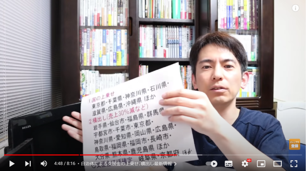 山田さんが各自治体の対応について解説している場面。手には、地域が書かれた紙を持っている。
