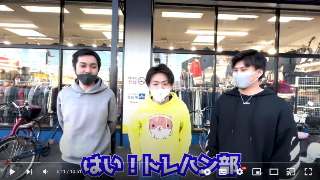 じん先生、たっきーさん、サトシ先生が店舗の外で並んでいる様子。動画の内容の説明を始める場面。